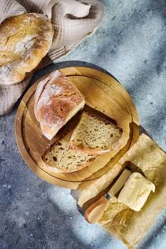 Top view of sliced rustic bread on wooden cutting board with butter Stock Photos