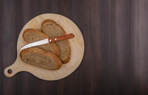 Top view of sliced seeded brown cob with knife on cutting board on wooden b.. Foto stock