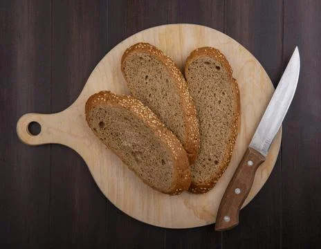 Top view of sliced seeded brown cob with knife on cutting board on wooden b.. Foto stock