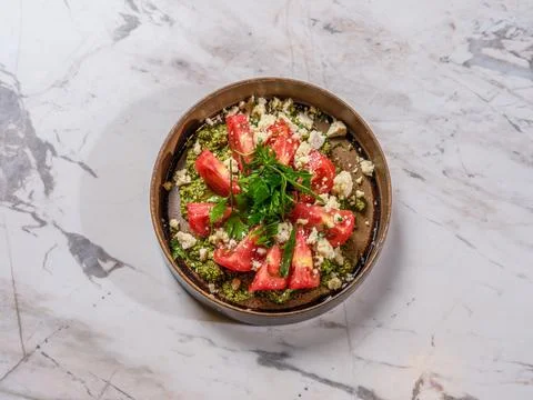 Top view of sliced tomatoes over green pesto and cottage cheese on marble 스톡 사진