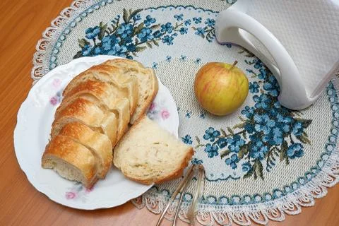Top view of sliced white bread and a red apple on an embroidered tablecloth. Stock Photos