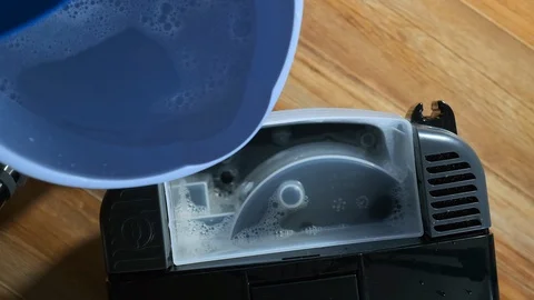The top view slow-mo man pours the detergent into the vacuum cleaner Stockbeeldmateriaal 122075259