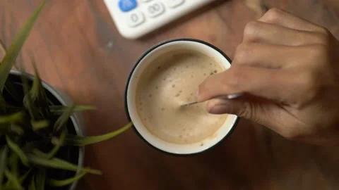 Top view slow motion of hot coffee cup in the morning. Female hand steering coff Stock Footage 141355372