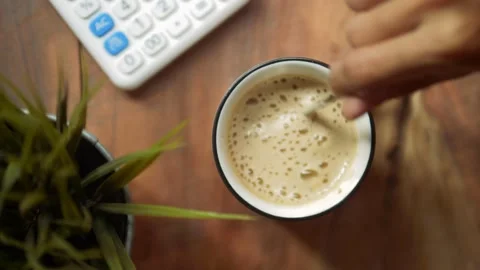 Top view slow motion of hot coffee cup in the morning. Female hand steering coff Stock Footage 141355387