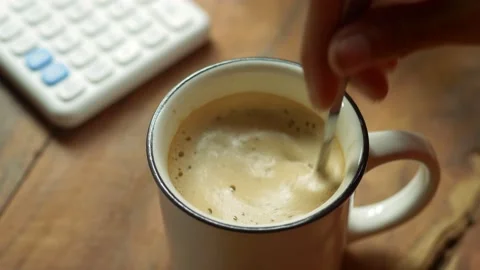 Top view slow motion of hot coffee cup in the morning. Female hand steering coff Stock Footage 141355420