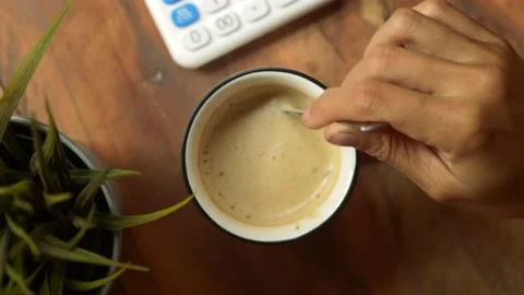 Top view slow motion of hot coffee cup in the morning. Female hand steering coff Stock Footage 141355484