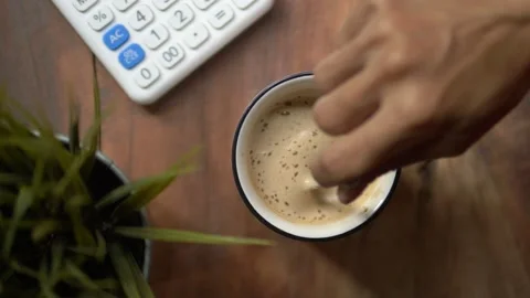 Top view slow motion of hot coffee cup in the morning. Female hand steering coff Stock Footage 141359557