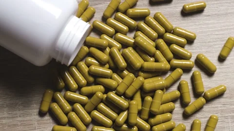 Top view slow rotation shot of yellow capsules and pills on wooden table Stock Footage 342239860
