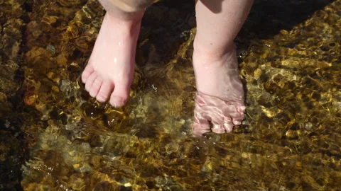 Top view of small bare feet splashing in water on sunny day Stock Footage 307556170