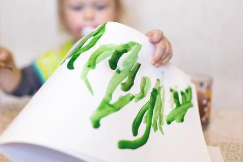 Top view of the small child is drawing with bright paints on paper, close up. Stock Photos