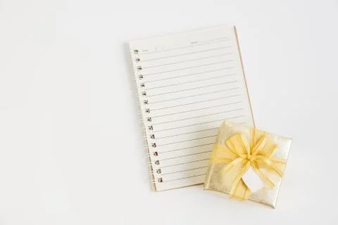 Top view of small notebook with gold gift box on white background Stock Photos