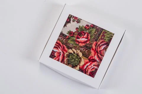 Top view on small white gift box with soft cotton scarf with colorful floral Фото