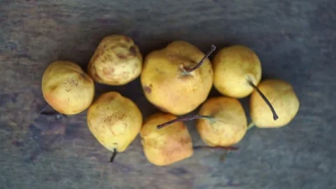 Top view of small yellow wild pears arranged on a rustic wooden table, slow moti Stock Footage 341888187
