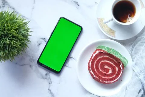 Top view of smart phone, tea and a cake on tiles background Stock Photos
