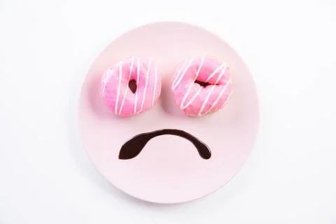 Top view of smiley sad face worried about overweight made on dish with donuts Stock Photos