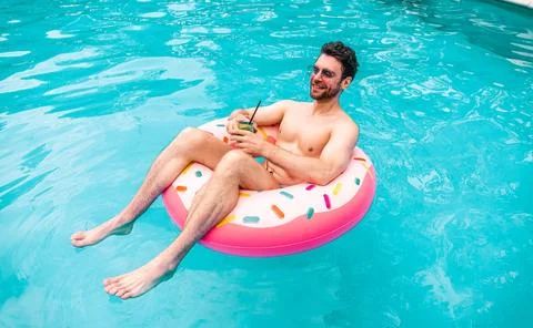 Top view of smiling guy resting on the inflatable ring in the swimming pool and Foto stock