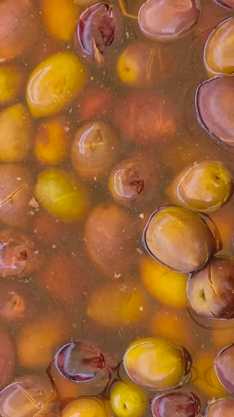 Top view smooth camera motion over a vat of marinated green and brown olives Stock Footage 344771663