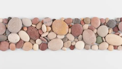 Top view of smooth, multicolored pebbles arranged on a white background. Perf Stock Photos