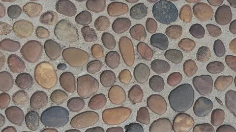 Top view of a smooth pebble stone walkway embedded in concrete cement. Stock Photos