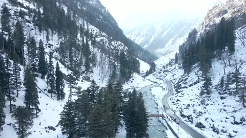 Top view of snow covered valley with river flowing and road constructed besides. Stock Footage 202603342