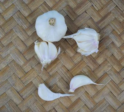 Top view of some white colored garlic seeds scattered beside a white garlic Stock Photos
