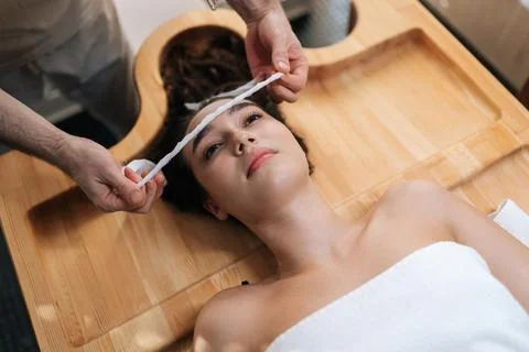 Top view of spa master applying bandage to forehead of young woman client in Stock Photos