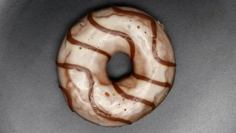 Top View Spinning Donut Glazed With White Icing With Brown Curls On A Black Plat Stock Footage 150090834