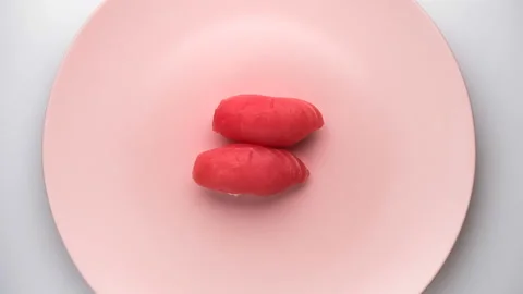 Top view of spinning two tuna nigiri sushi on the spinning pink plate. Stock Footage 127106567