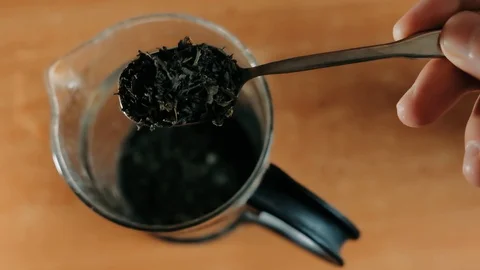 TOP VIEW: spoon adding natural herbs tea in glass teapot. Making tea. Stock Footage 129732541