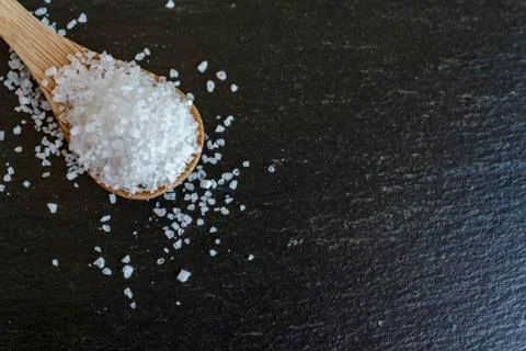 Top view of spoon with coarse grained sea salt on black background with copy  Stock Photos