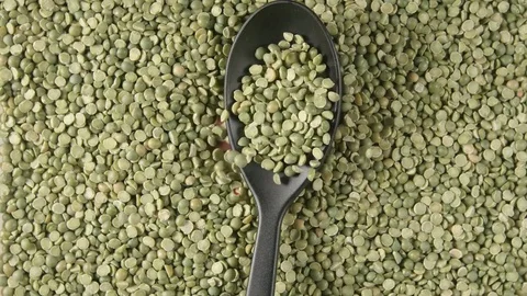 TOP VIEW: Spoon with a green peas falls on a green peas (slow motion) Vídeo Stock 74496531
