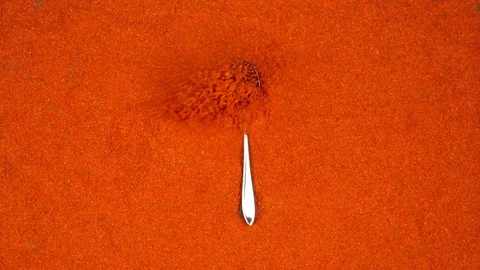 TOP VIEW: Spoon with a pepper powder falls on a red pepper powder - Slow Motion Stock Footage 90240029