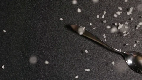 TOP VIEW: Spoon with salt falls on a black table (slow motion) Stock Footage 72623426