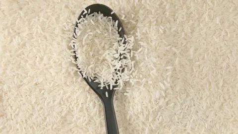 TOP VIEW: Spoon with a white rice falls on a rice (slow motion) Video stock 74496520