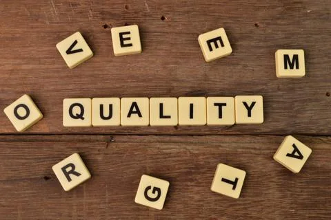 Top view of square letters with text QUALITY over wooden background Stock Photos
