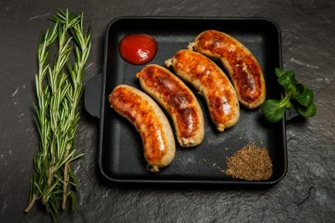 Top view square pan with four sausages, rosemary and basil 写真素材
