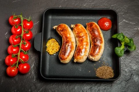 Top view square pan with sausages, caraway, mustard, basil, and tomatoes 写真素材