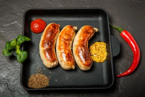 Top view square pan with three sausages and mustard Stock Photos