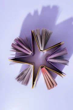 Top view of stack of books in shape of star on violet surface Stock Photos