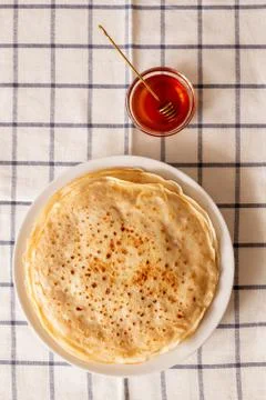 Top view of stack of fresh pancakes on plate and small bowl of flower honey 스톡 사진