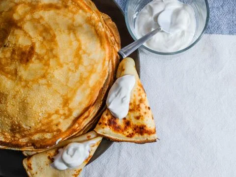 Top view on a stack of rosy freshly baked pancakes on a brown plate. Stock Photos