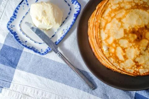 Top view on a stack of rosy freshly baked pancakes on a brown plate. Stock Photos