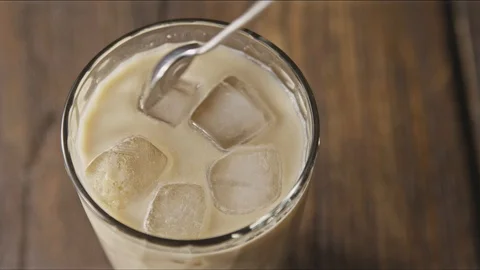 Top view of stirring ice coffee beverage with milk with spoon. Stock Footage 129637919
