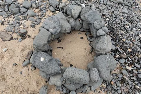 Top view of a stone campfire ring built from large rocks on a sandy beach Stock Photos