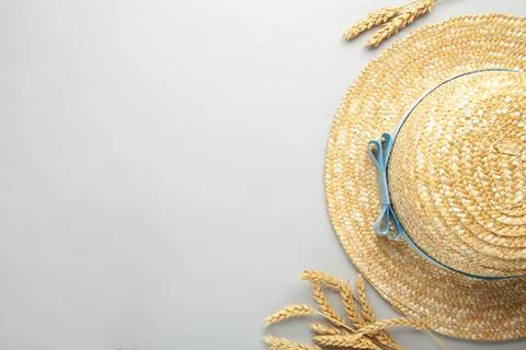 Top view of straw beach hat with blue ribbon and spikelets on grey background Stock Photos