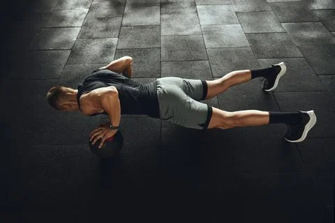 Top view of strong man doing push up exercise with one hand on medicine ball Stock Photos