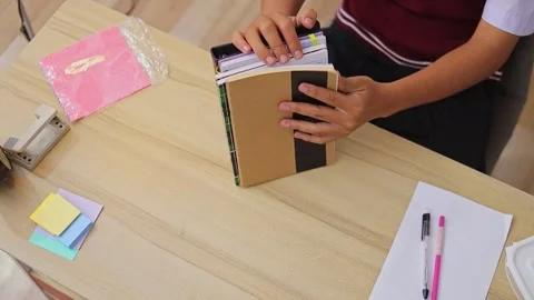 Top view of student arranging stack of notebooks and leather planner on wooden Stock Footage 335017781