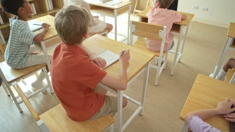 Top view of students sitting in classroom with school supplies on desks Stock Footage 339340519