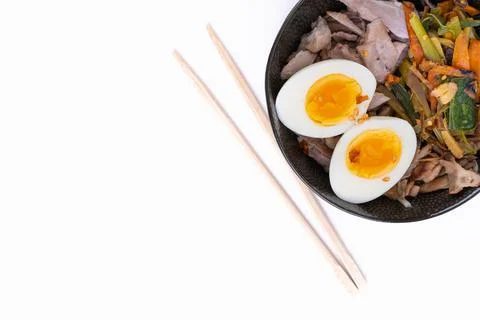 Top view studio shot of black bowl of ramen noodles with boiled eggs, veggies Stock Photos