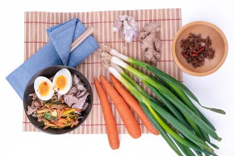 Top view studio shot of black bowl of ramen noodles with boiled eggs, veggies Stock Photos